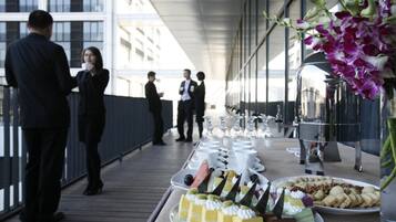 A buffet setup on a balcony with various desserts and a floral arrangement.