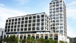 Un hotel moderno de varios pisos con un edificio central destacado y una estructura más alta a la derecha.