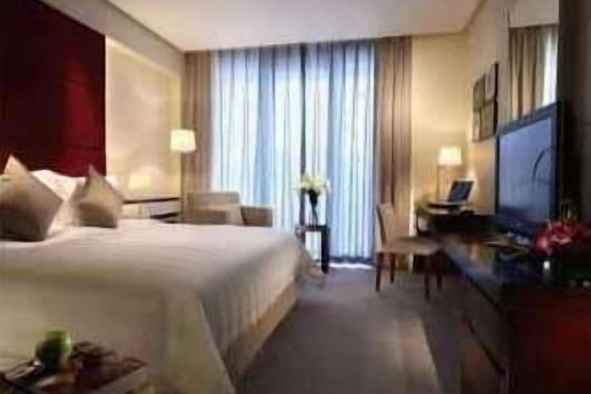 Habitación de hotel con una cama grande, un escritorio con una computadora portátil, un televisor y una silla.
