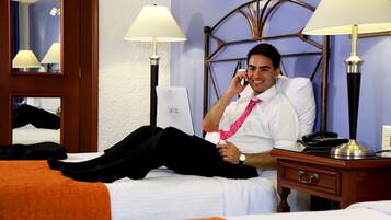 A hotel room with a bed, a bedside table with a lamp, and a mirror on the wall.