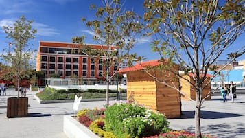 Un hotel de fachada roja, estructura de madera y jardín ajardinado con diversas plantas y flores.