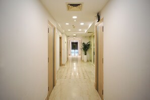 A hallway with a marble floor, wooden doors, and recessed lighting.