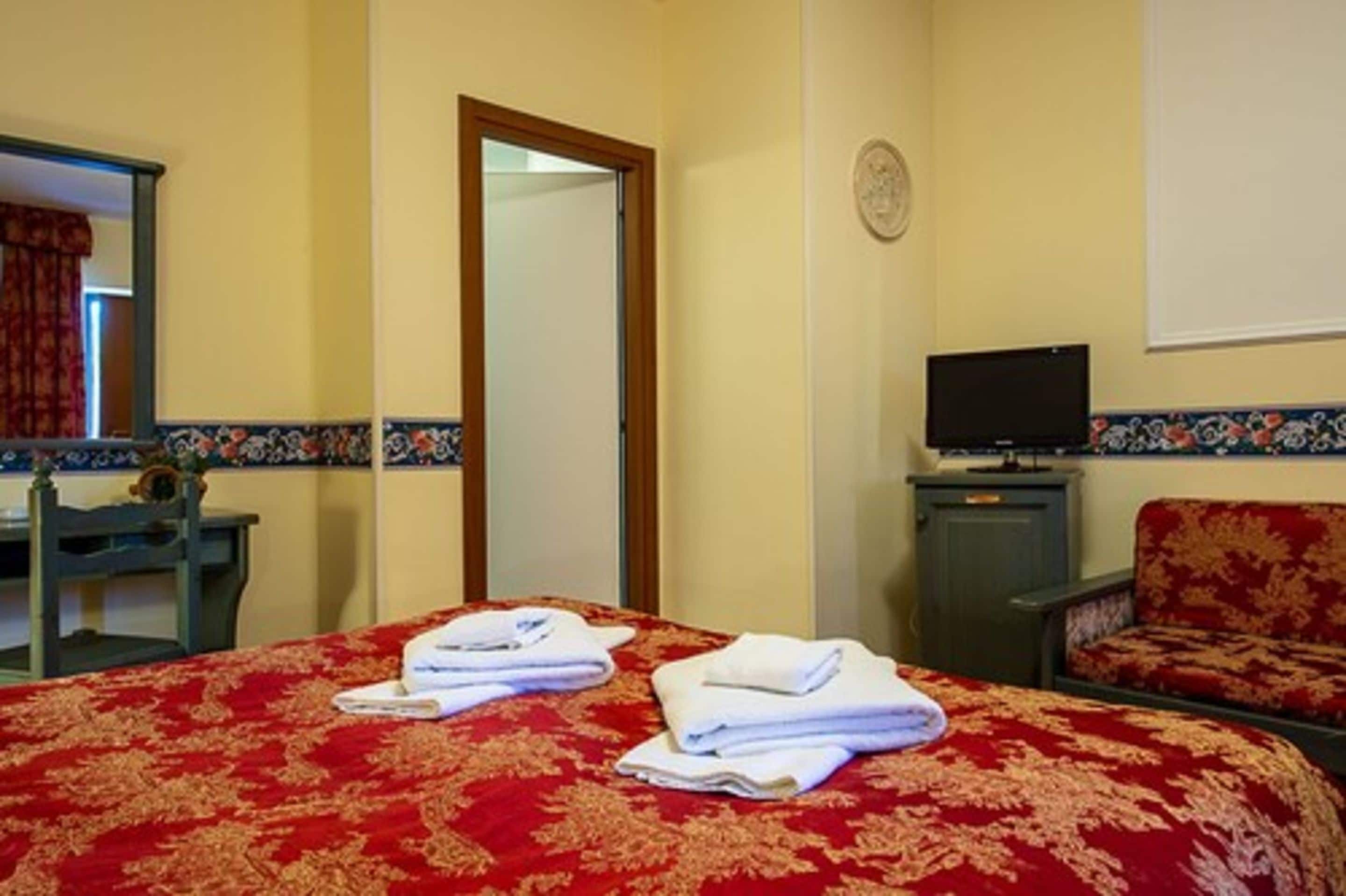 A hotel room with a bed, a television, a desk, and a chair.