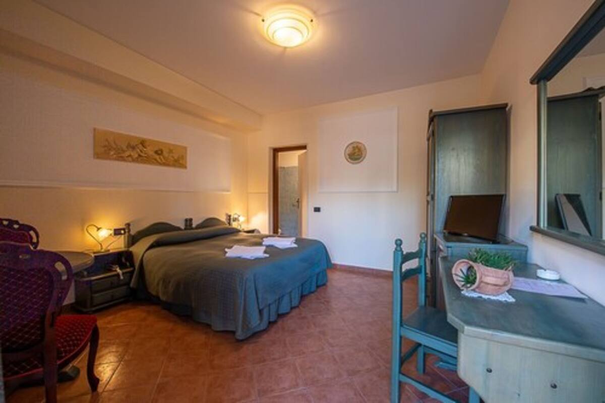 Une chambre à coucher comprenant un lit, une table de chevet, une chaise, un bureau et une petite plante en pot.