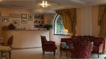 A hotel lobby with a bar area, seating arrangements, and a large window with curtains.