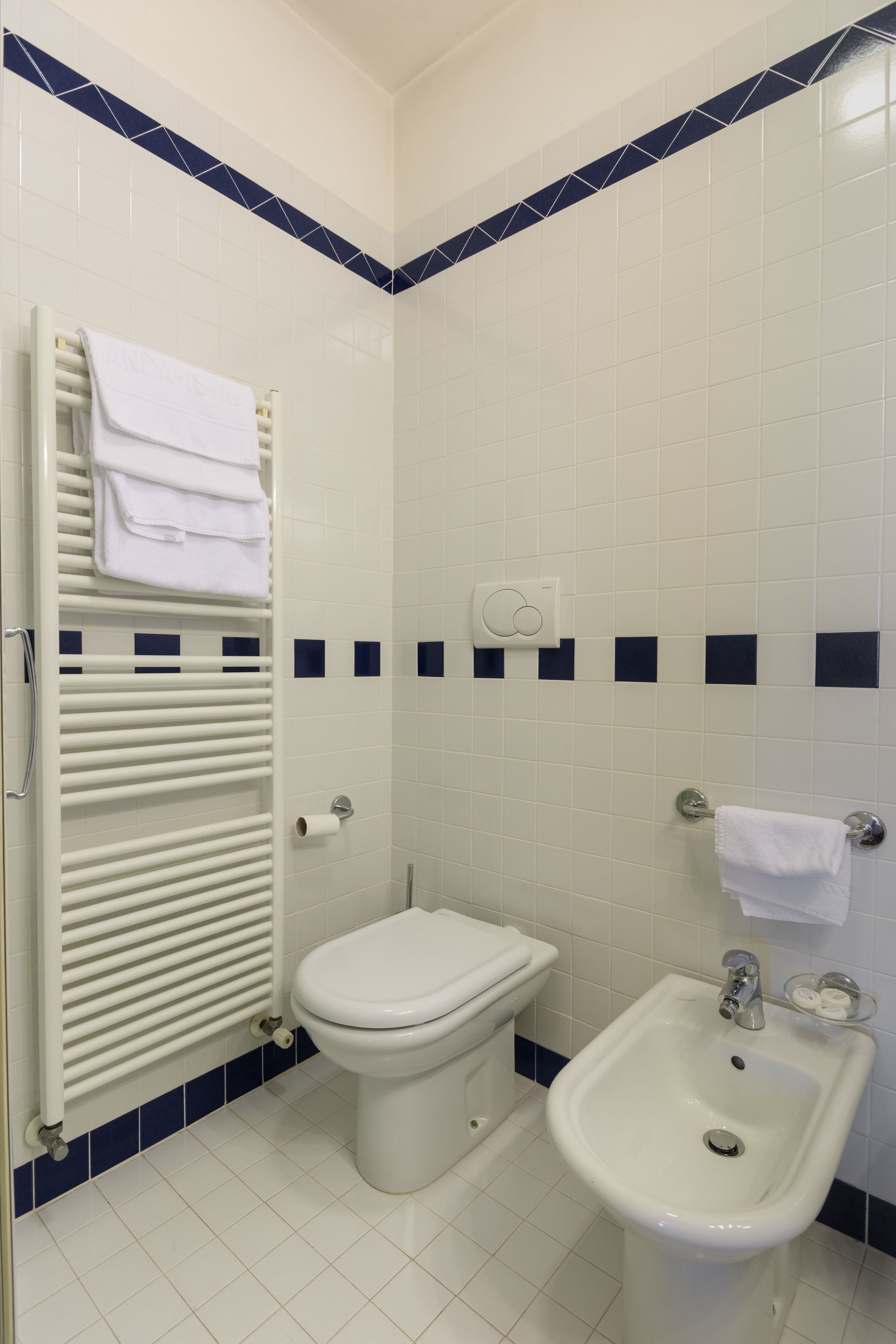 Un baño con inodoro, bidé y barra para toallas.