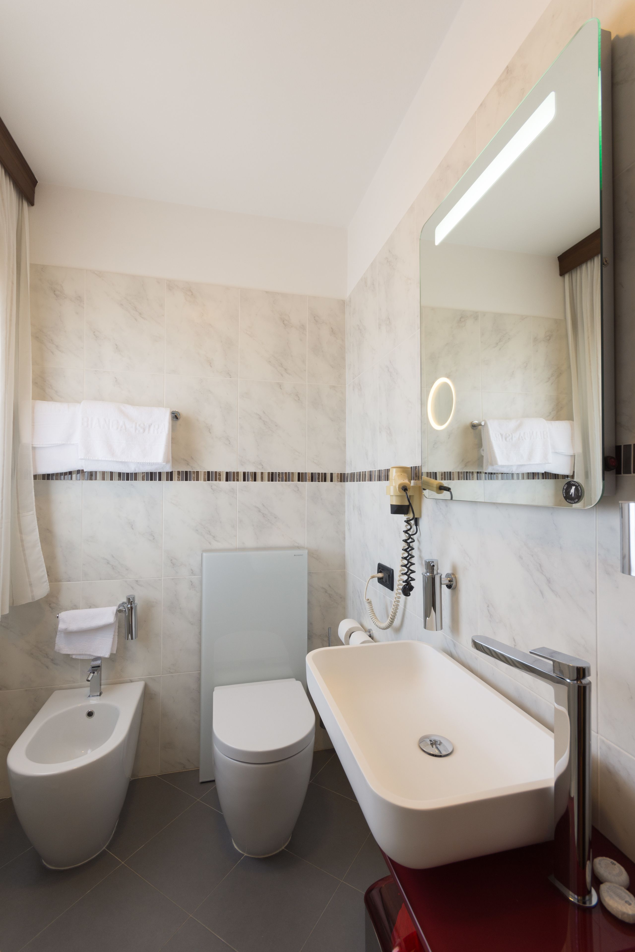 A modern bathroom with a bidet, toilet, and sink.