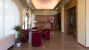 A hotel lobby with a reception desk, seating area, and a potted plant. - Park Hotel Ristorante Ca' Bianca (Istrana)