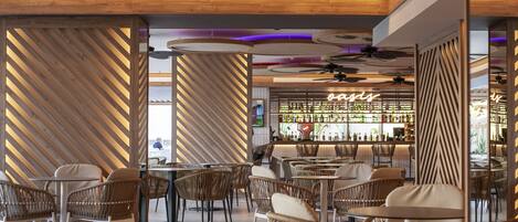 A modern bar area with wicker furniture and a neon sign.