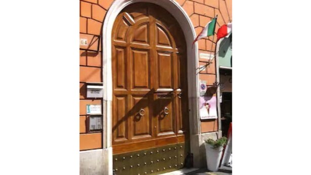 A large wooden door with a decorative metal grille, set in a brick wall. - My Monti Place (Rome)