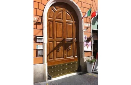 A large wooden door with a decorative metal grille, set in a brick wall.