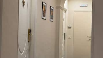 A hallway with white doors, a carpeted floor, and two framed pictures on the wall.