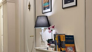 A hallway with a white door, a radiator, a lamp, and framed pictures on the wall. - My Monti Place (Rome)