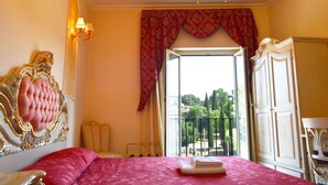 A room with a bed, a chandelier, a window with a view, and a wardrobe. - Imperial Rooms (Rome)