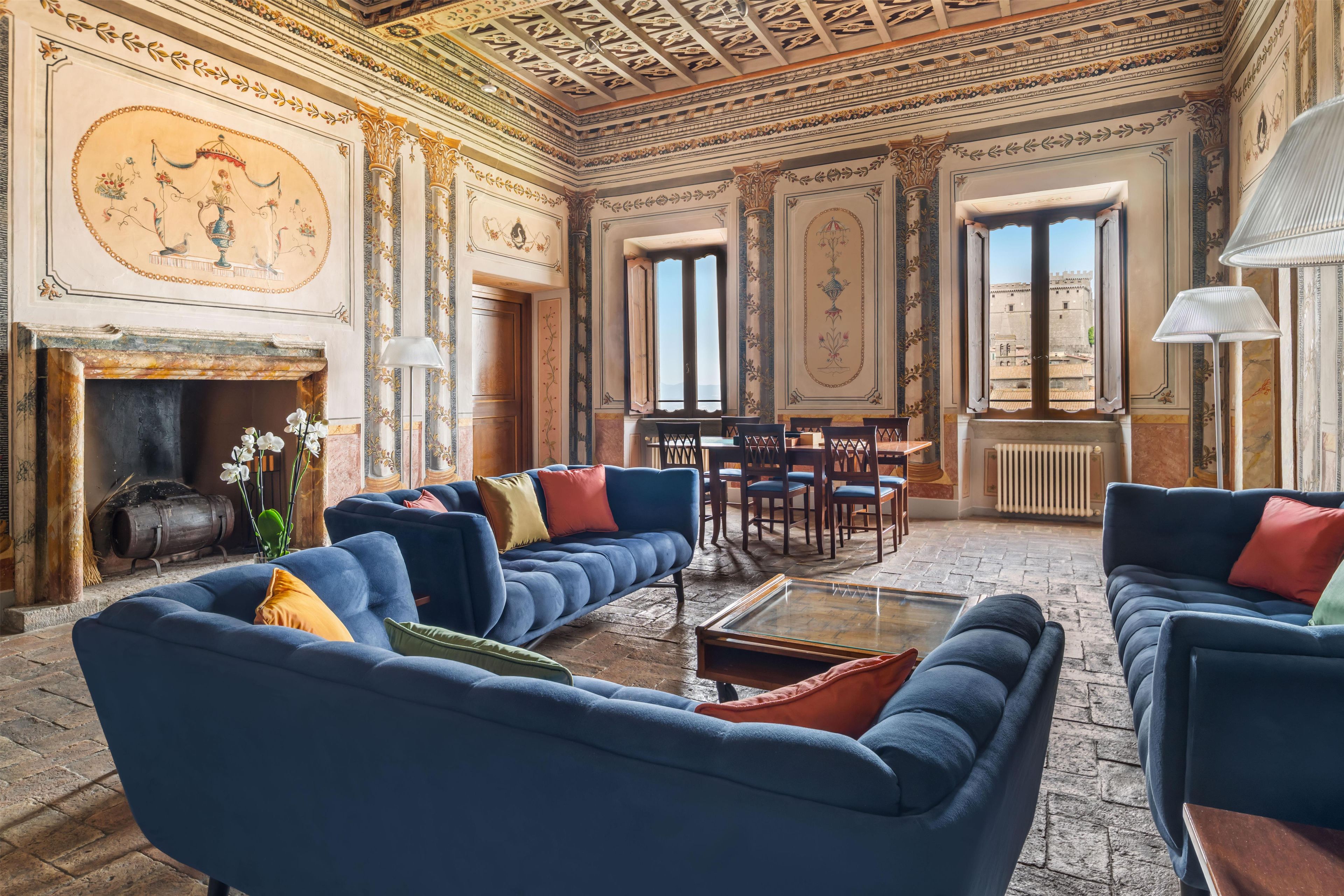 A room with a fireplace, blue sofas, a coffee table, and a view of a castle through a window.