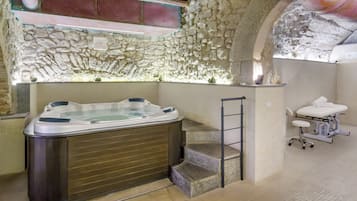 Relax in a serene spa area with a hot tub and adjacent massage room.