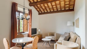 A living room with a round table, patterned chairs, a sofa, and a TV. - Hilton Vacation Club Palazzo Catalani & Soriano (Soriano nel Cimino)