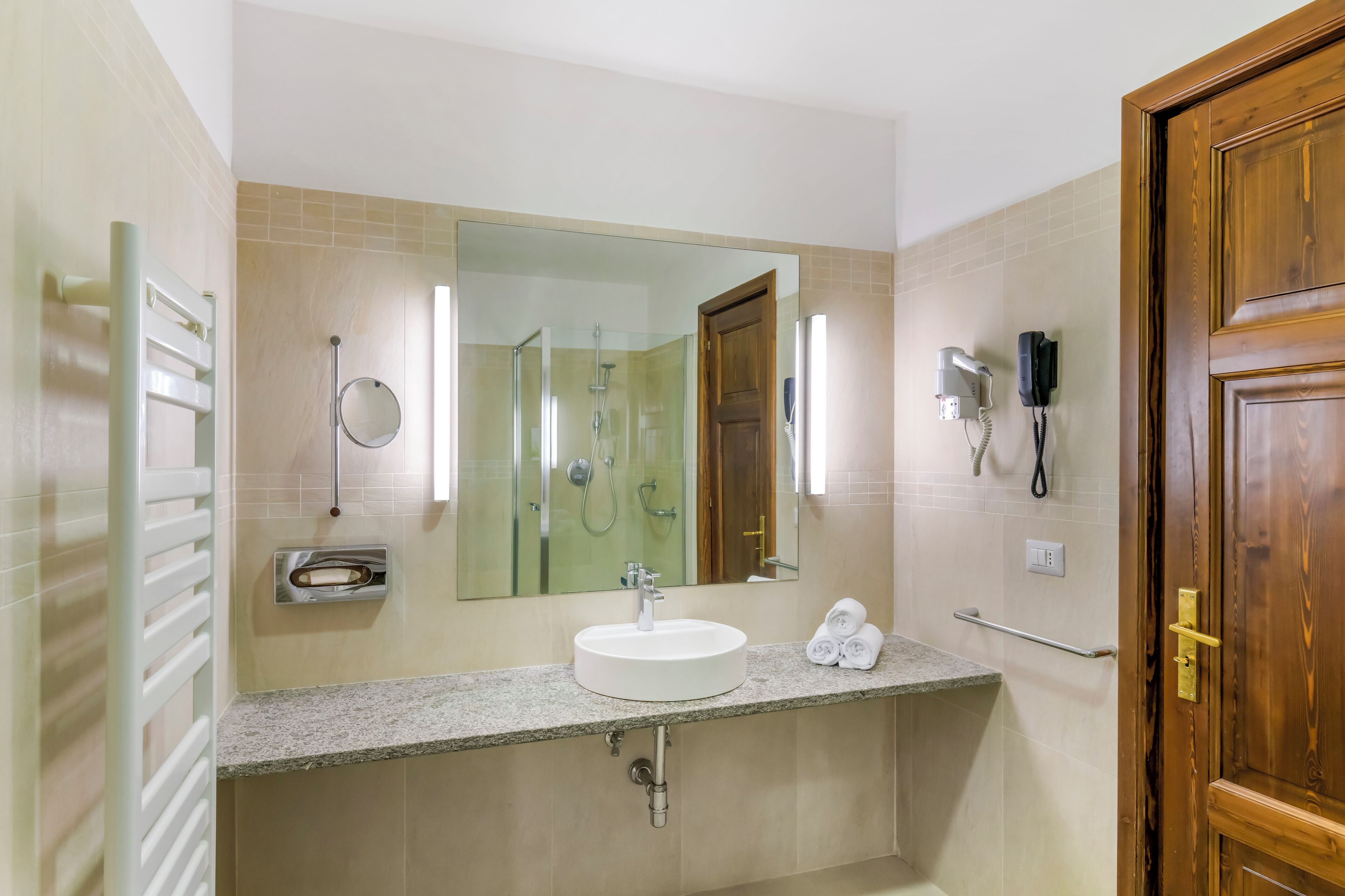 Een badkamer met een wastafel, spiegel, handdoekhouder en douche.