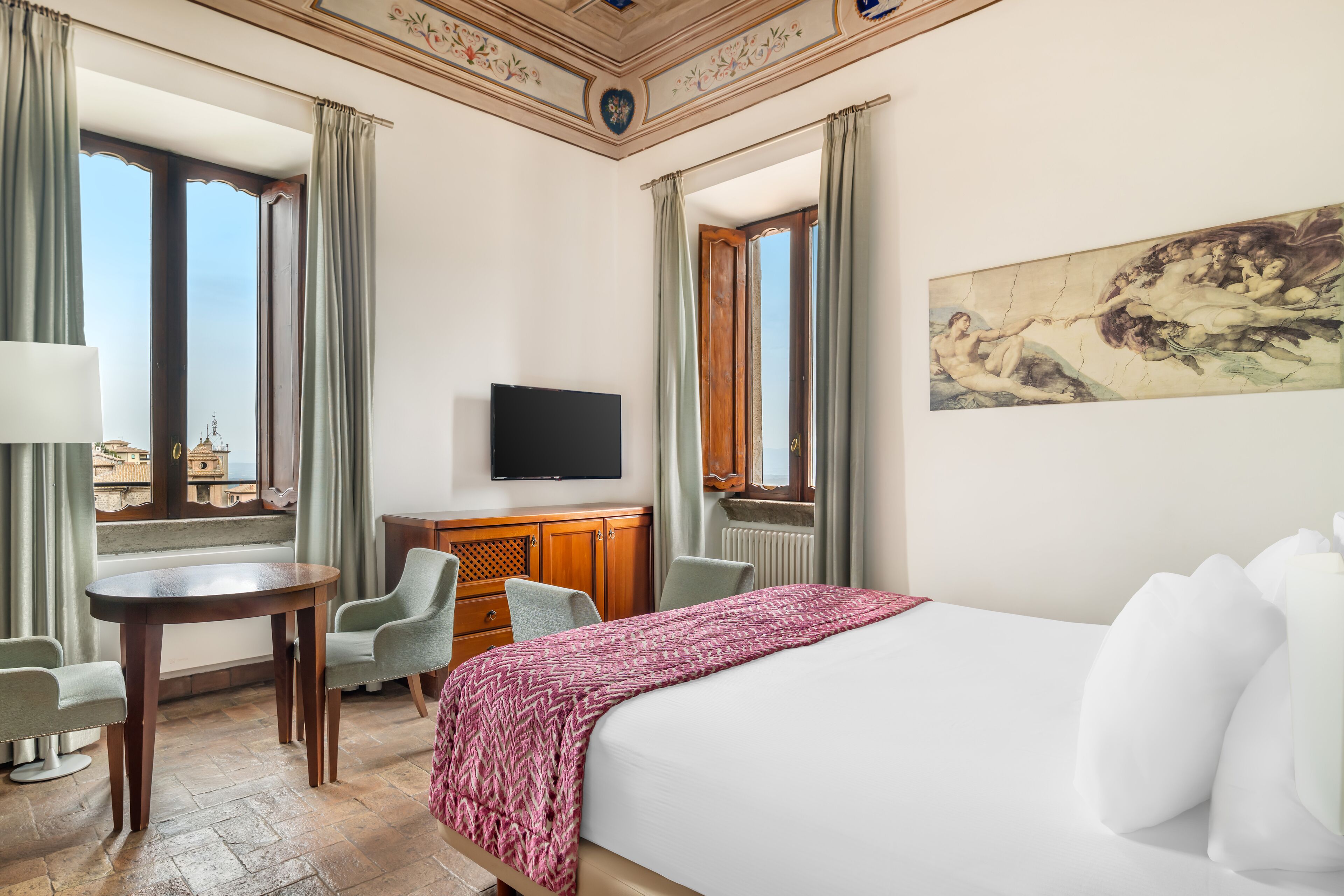 Una camera d'albergo con un letto, una televisione, una scrivania e una sedia.