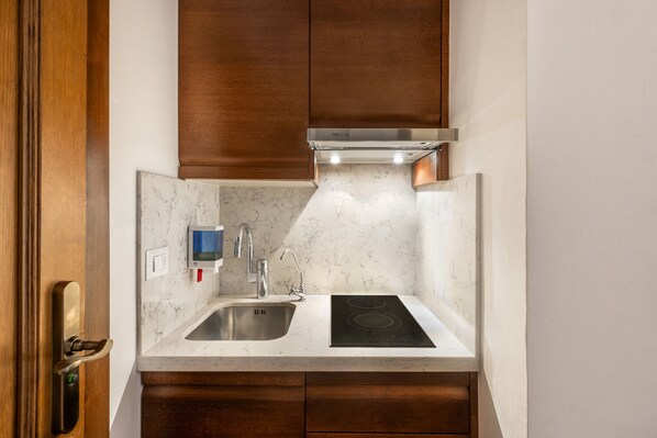 A compact kitchen with a built-in sink, a stove, and a wall-mounted faucet.