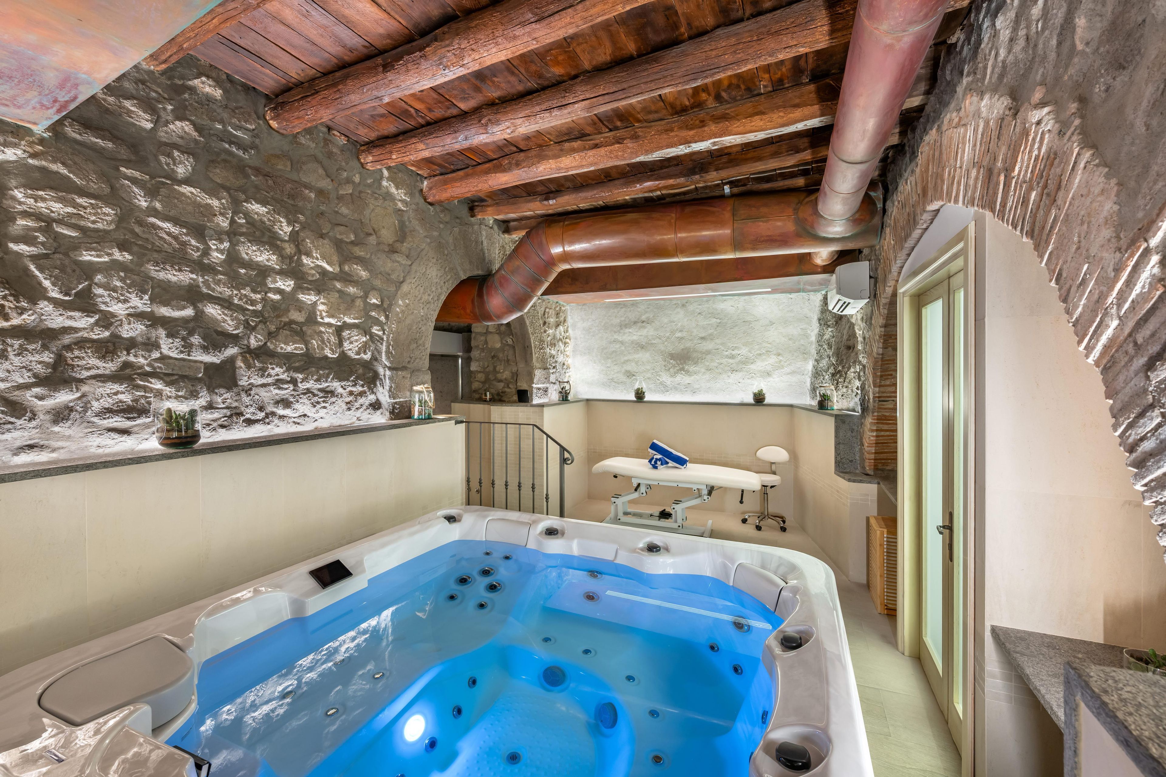 Ein Wellnessraum mit Whirlpool, Steinwänden und Holzboden.