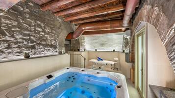 Ein Wellnessraum mit Whirlpool, Steinwänden und Holzboden.