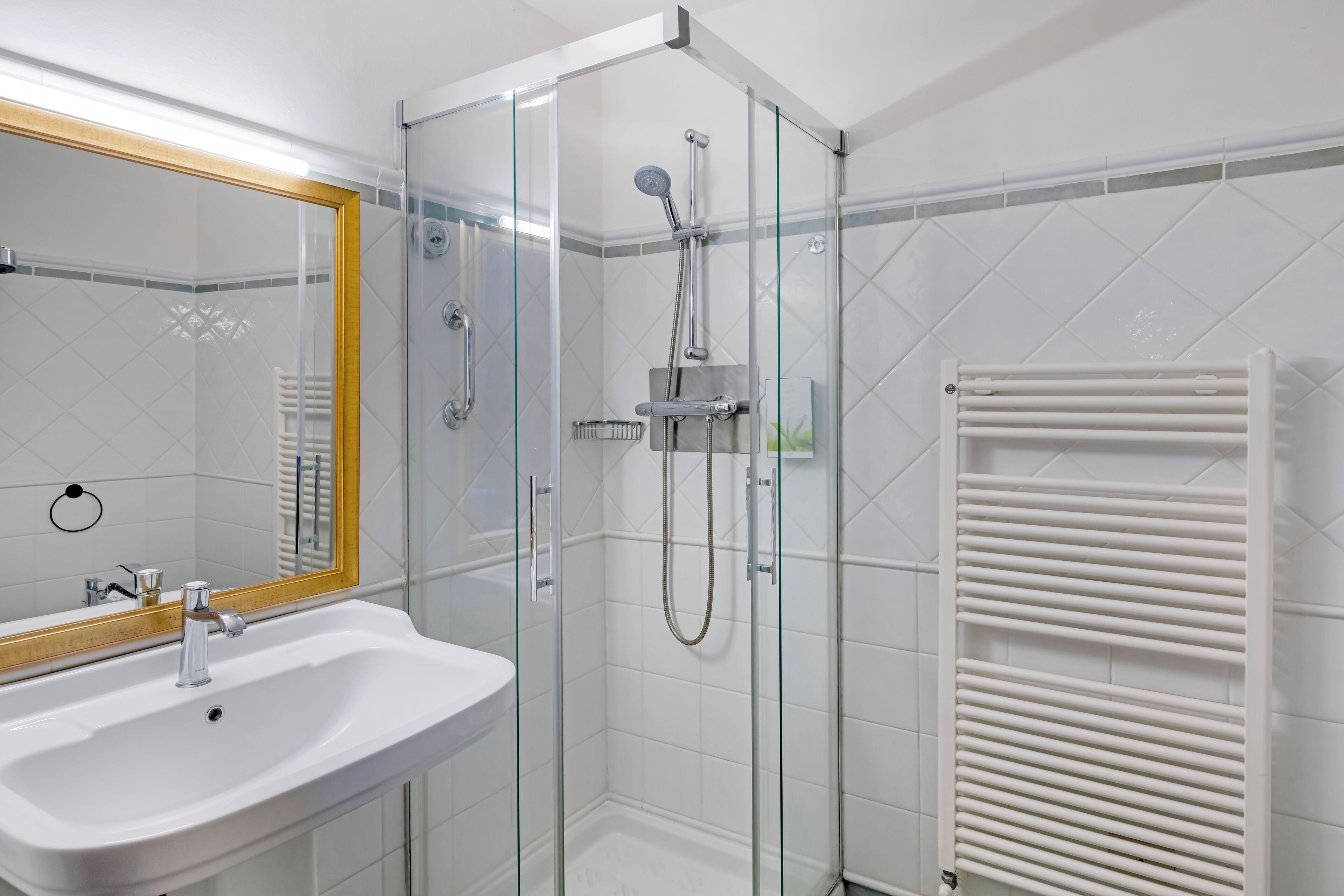 Une salle de bain moderne avec une douche à parois de verre, un lavabo blanc et un porte-serviettes.