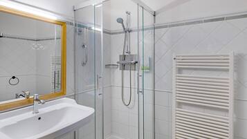 Une salle de bain moderne avec une douche à parois de verre, un lavabo blanc et un porte-serviettes.