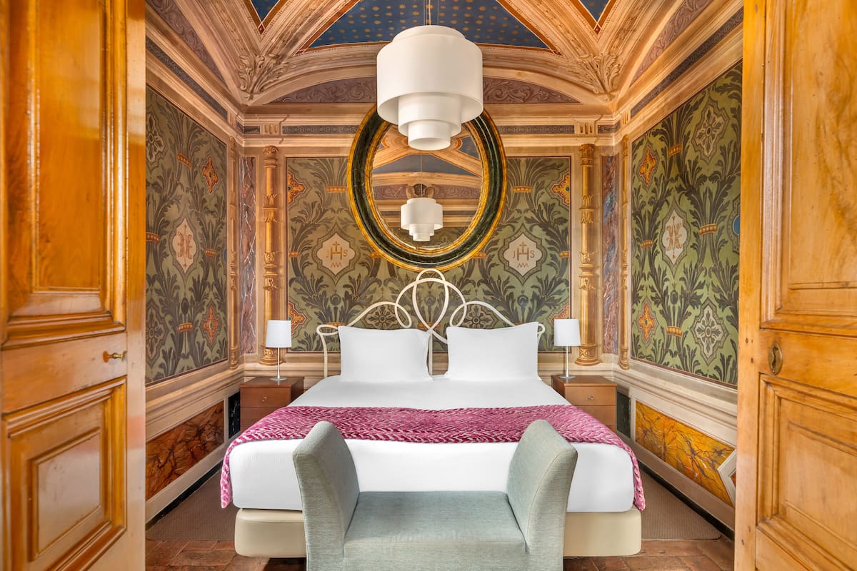 Una lujosa habitación de hotel con una cama grande, un techo ornamentado y elaborados diseños en las paredes.