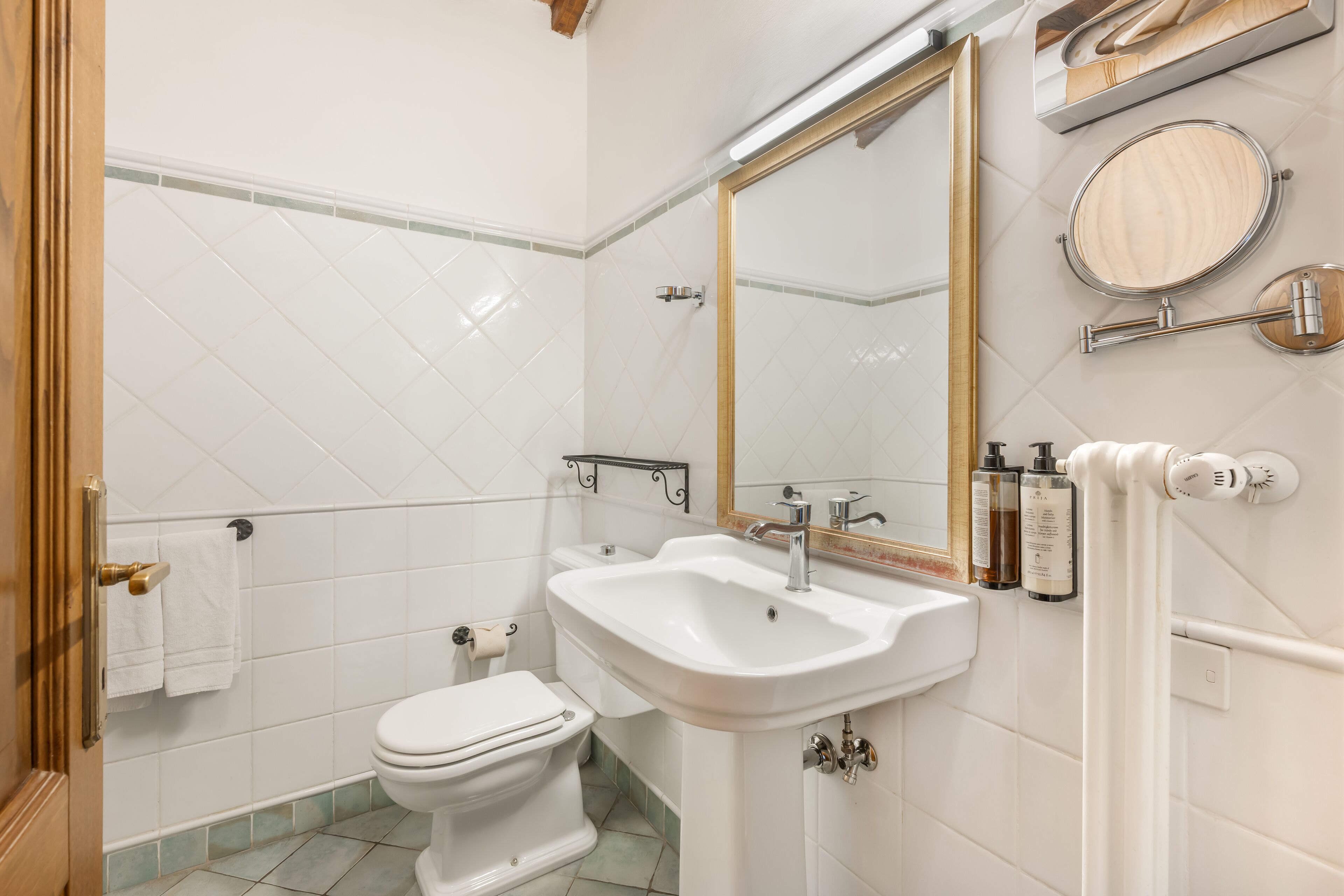 A bathroom with a white toilet, a sink, a mirror, and a towel rack.