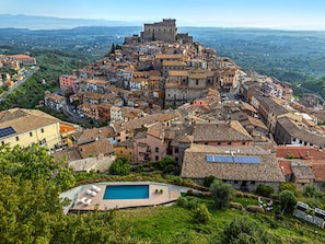 Un pueblo histórico con un castillo destacado, casas escalonadas y una zona de piscina.
