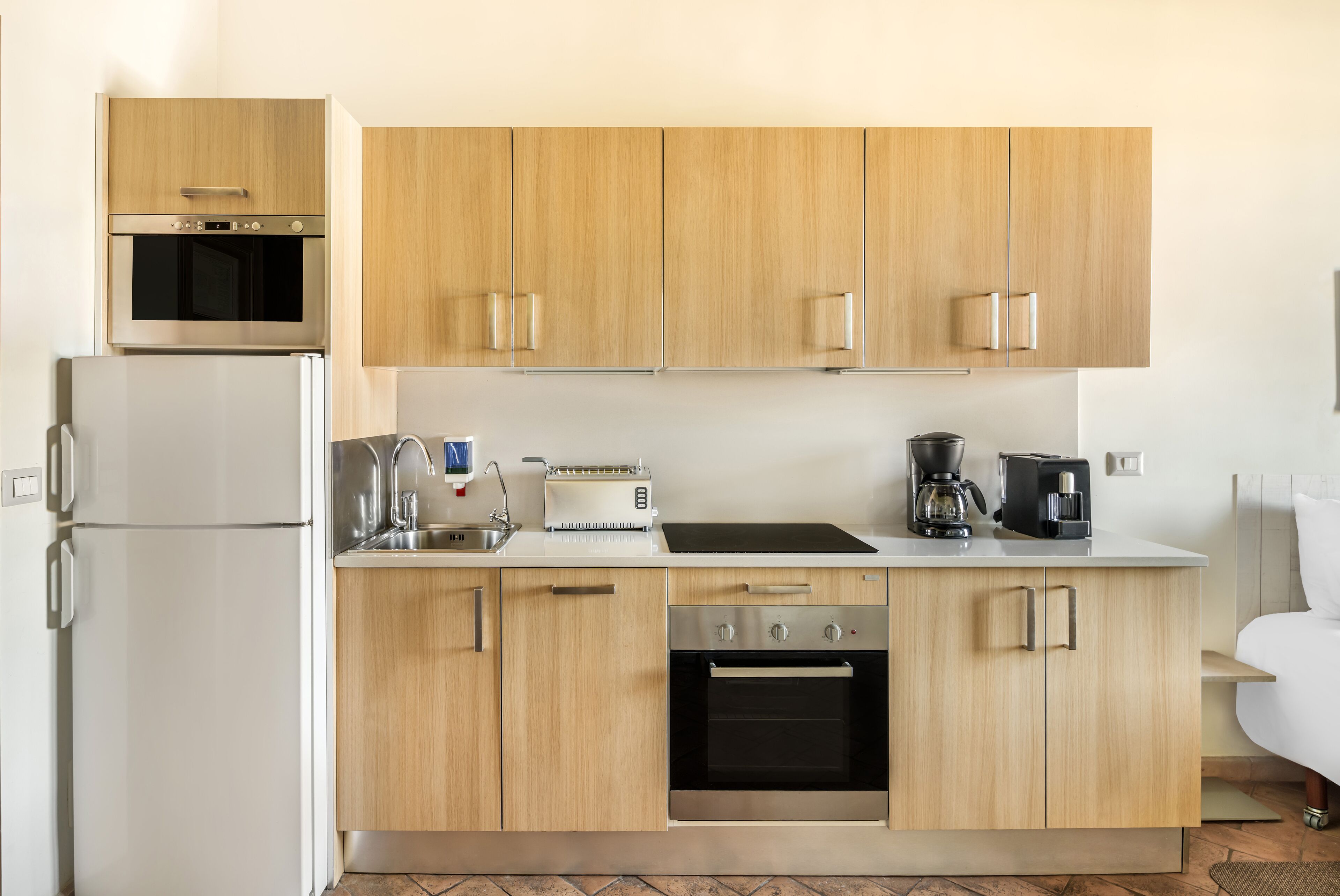 A modern kitchen with wooden cabinets, a built-in oven, a coffee maker, and a toaster.