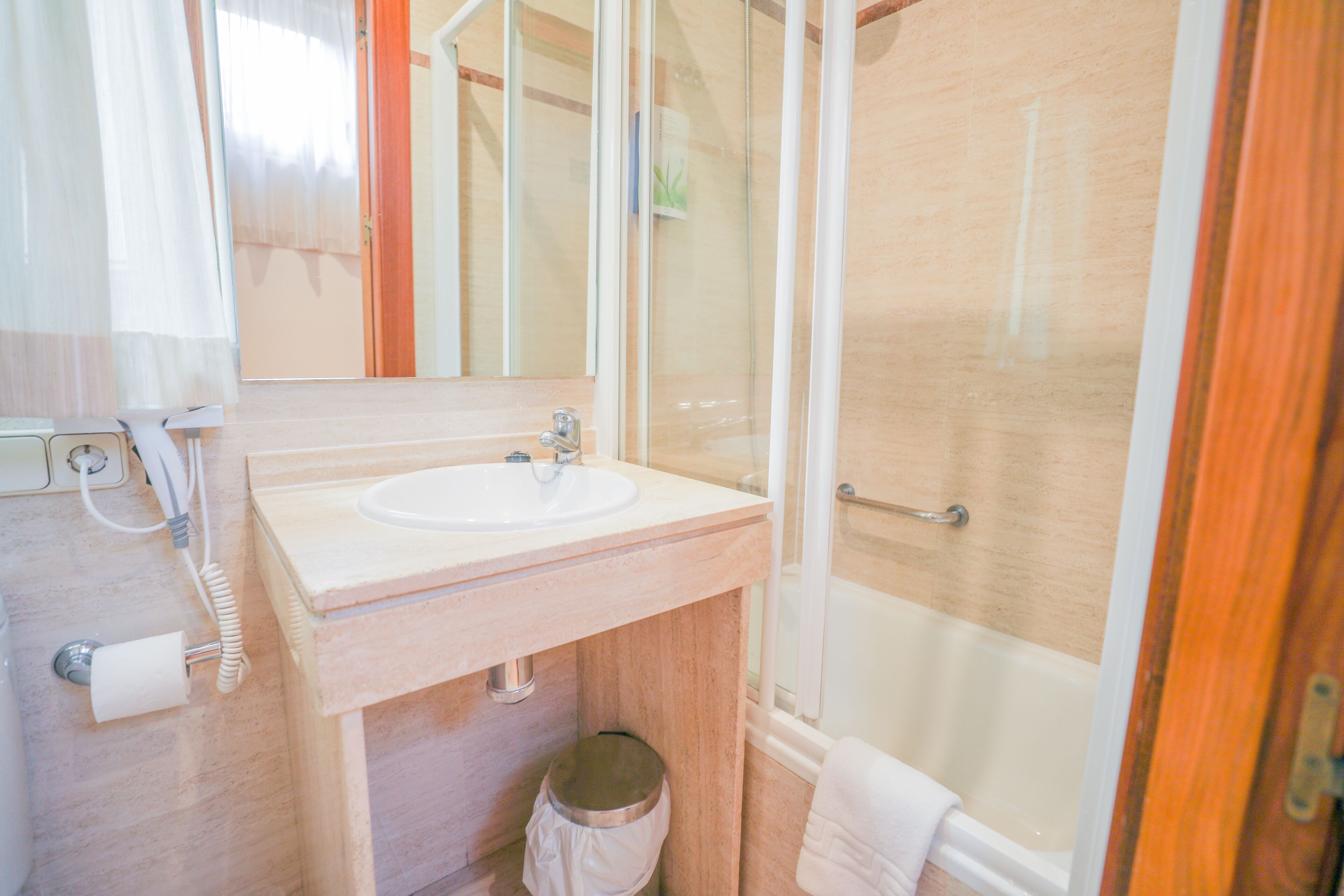 Baño con lavamanos, espejo y ducha.