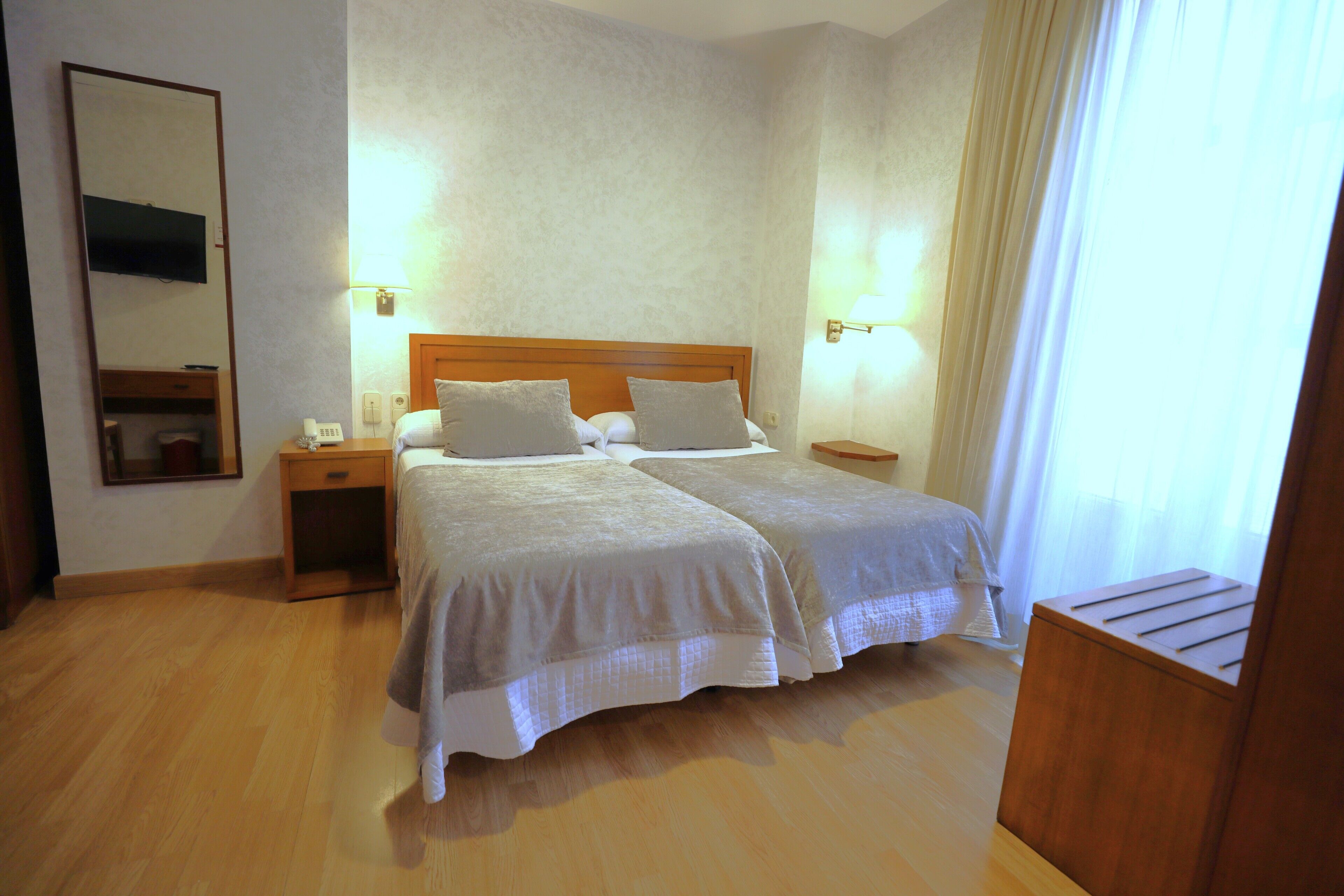 Una cama doble con dos almohadas, una mesita de noche con lámpara y un cabecero de madera.