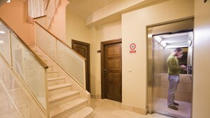 A hotel corridor with a wooden staircase, a closed elevator, and a no-smoking sign on the wall. - Hotel Granada Centro (Granada)