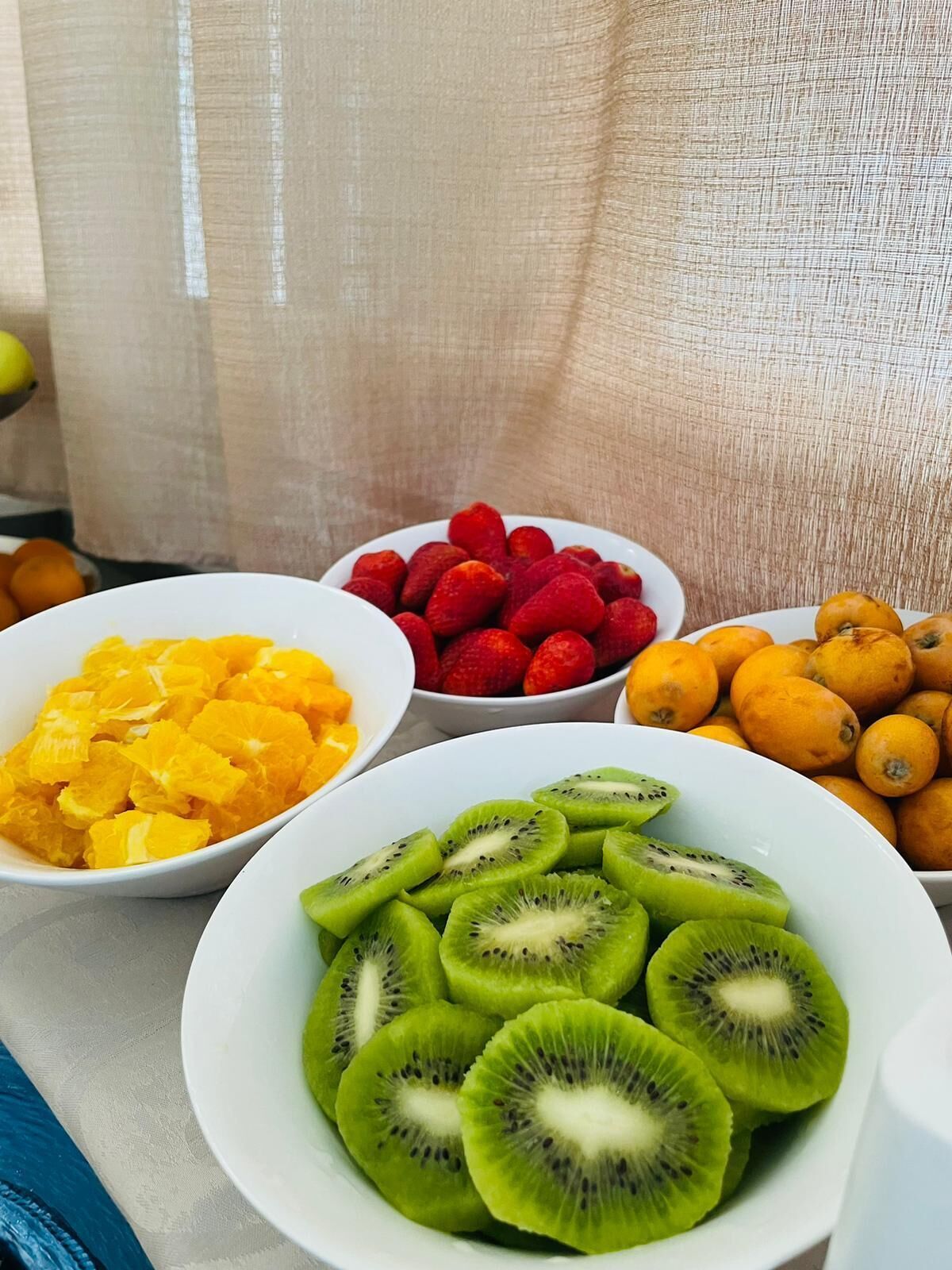Pöydällä on kulhoja, joissa on viipaloituja hedelmiä, kuten appelsiineja, mansikoita, kiivejä ja sitruunoita.