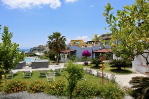 Un resort con piscina, mobiliario exterior y vista al mar.