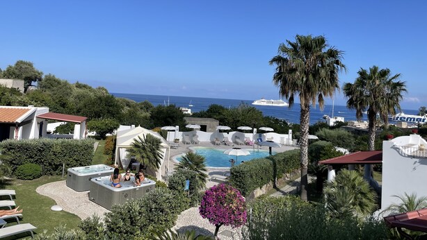 Zona de piscina con jacuzzis, sombrillas y vistas al mar.