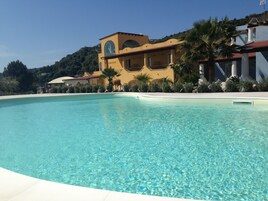 Una piscina al aire libre, sombrillas, sillones reclinables de piscina