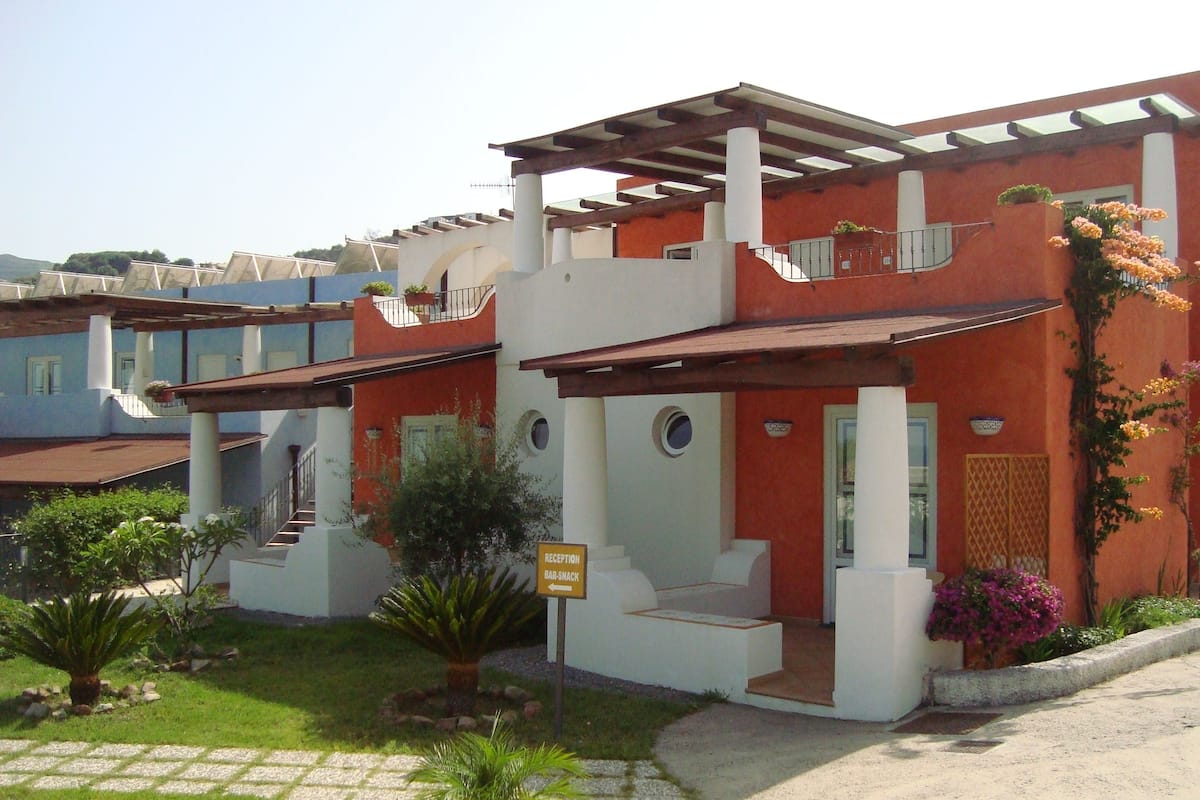 A modern building with a reception area, outdoor seating, and a garden.