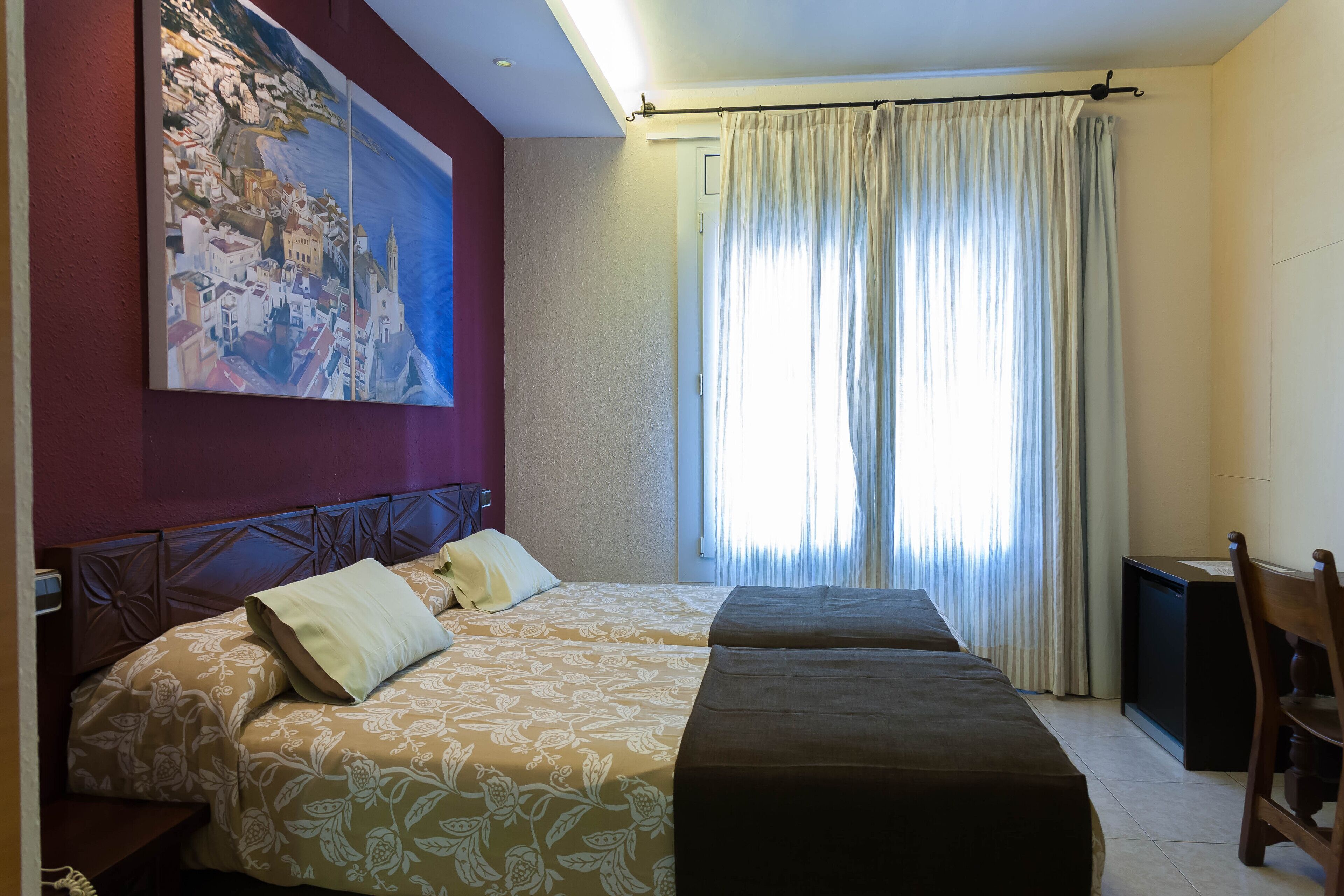 A hotel room with a bed, a desk, a chair, a television, and a painting on the wall.