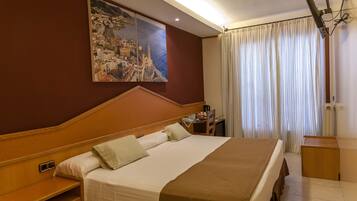 A hotel room with a large bed, a desk, a chair, a painting on the wall, and a window with curtains.