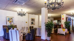 Un vestíbulo de hotel con sillones a rayas, un candelabro, una zona de bar y un extintor.