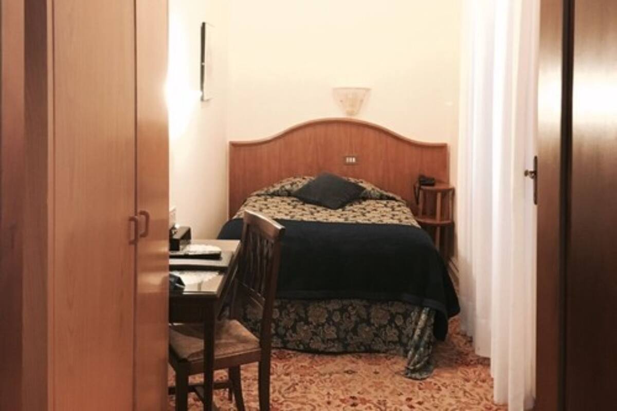 A small, cozy bedroom with a wooden bed, a desk, and a chair.