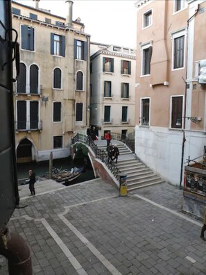 A narrow street with buildings on either side, a canal, and a staircase leading down to the canal. - Hotel Alla Fava (Venice)