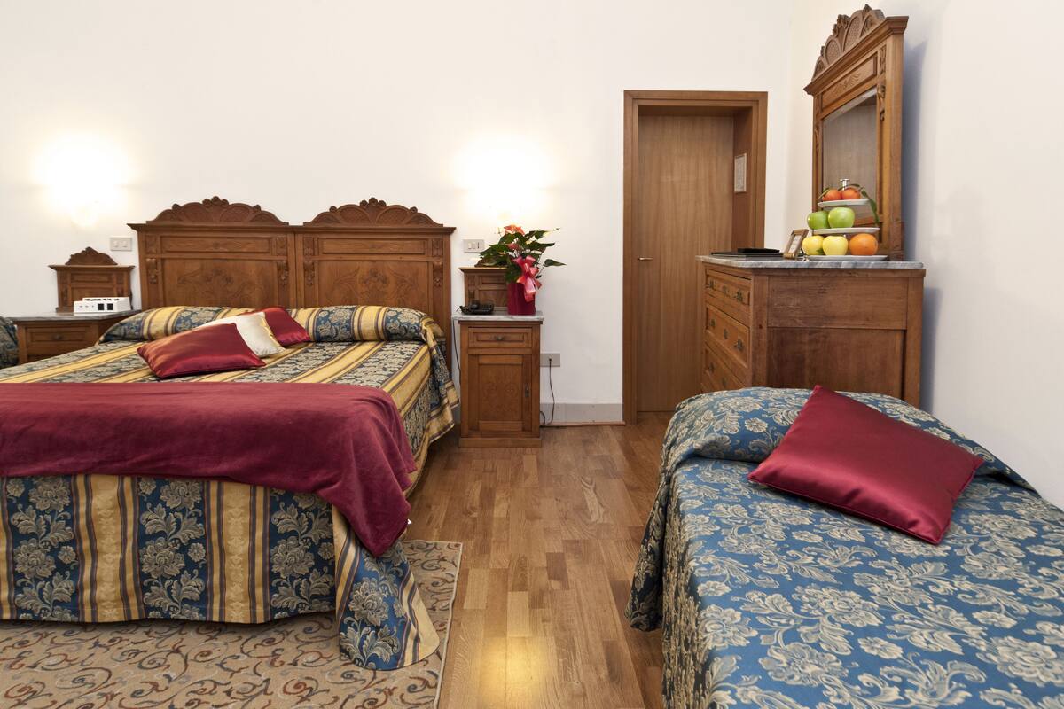 A bedroom with two beds, a dresser, a mirror, and a nightstand.