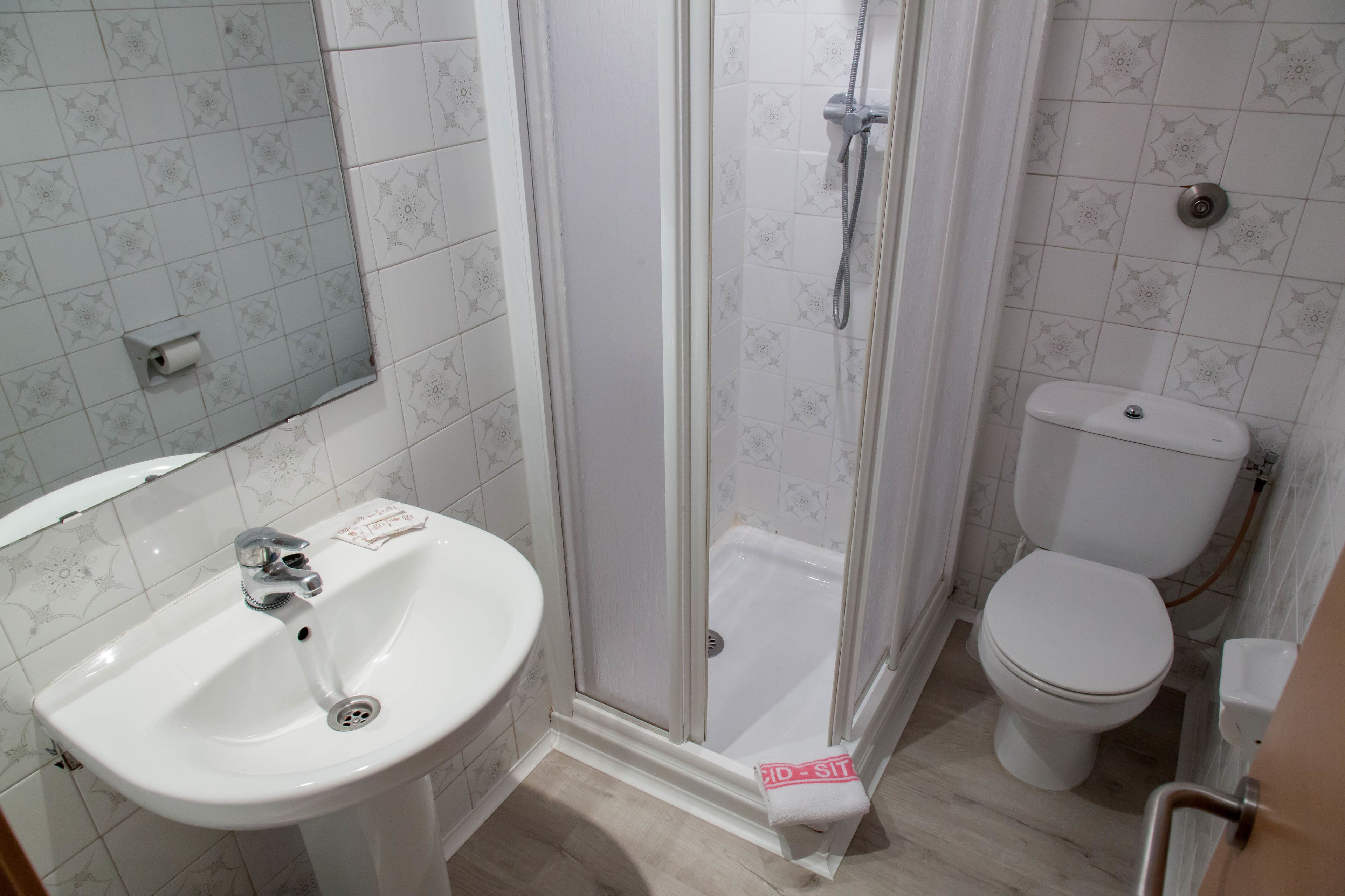 A bathroom with a white sink, toilet, and glass-enclosed shower.