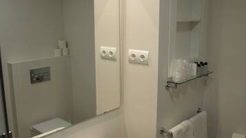 Un baño moderno con lavamanos, espejo y toallero blancos.