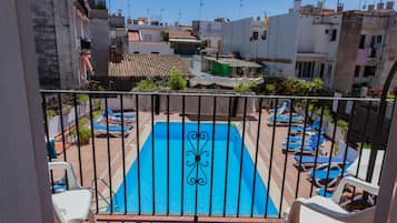 Een buitenzwembad, parasols bij het zwembad en ligstoelen