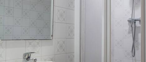 A bathroom with a white sink, a mirror, and a shower enclosure.